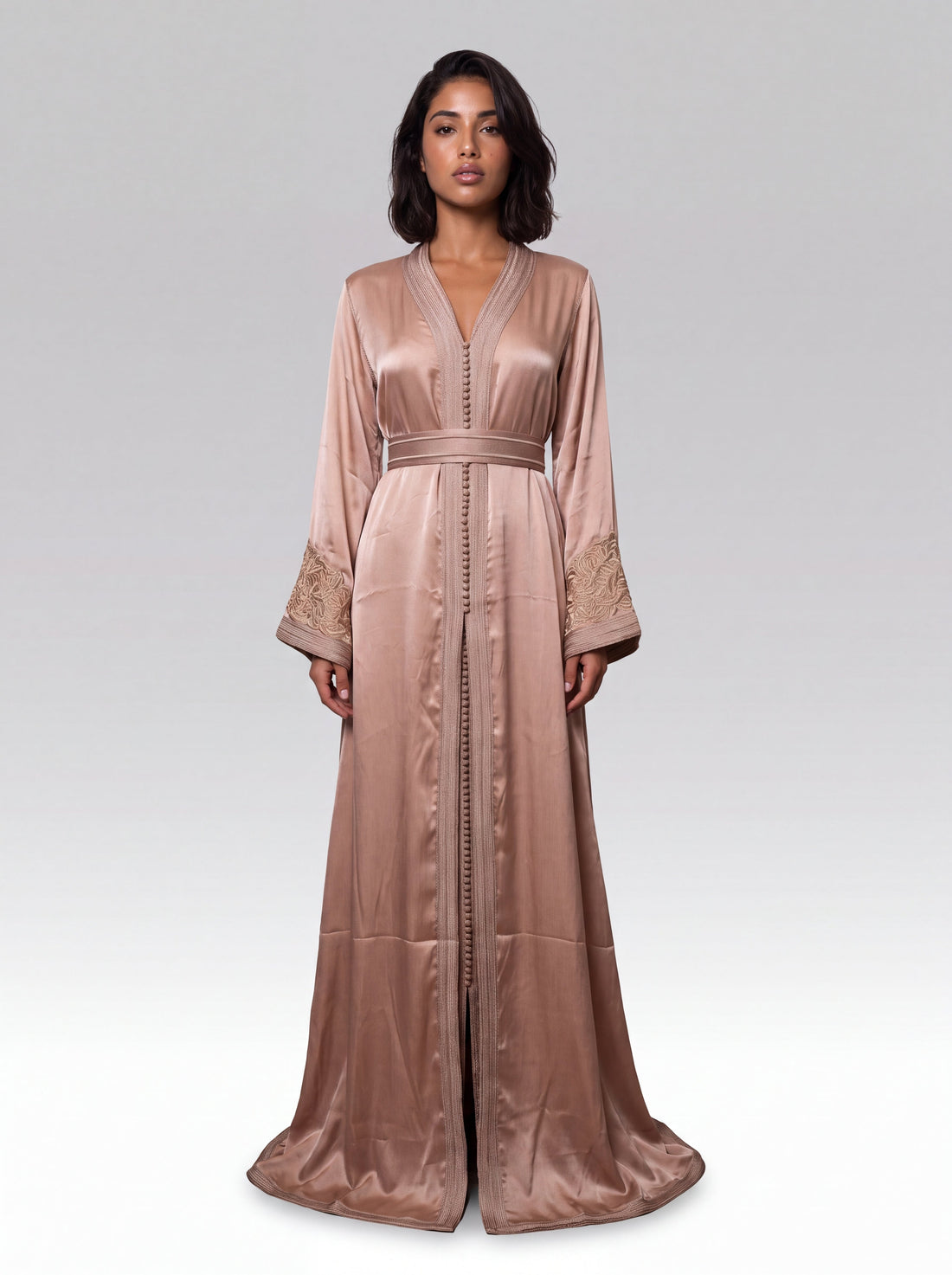 Caftan rose poudré porté en entier, arabesques champagne aux poignets, col en V boutonné et manches évasées, tenue de l'Aïd
